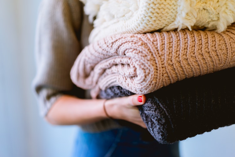 Ideas fotográficas de otoño para Instagram: una niña con suéteres doblados en sus manos